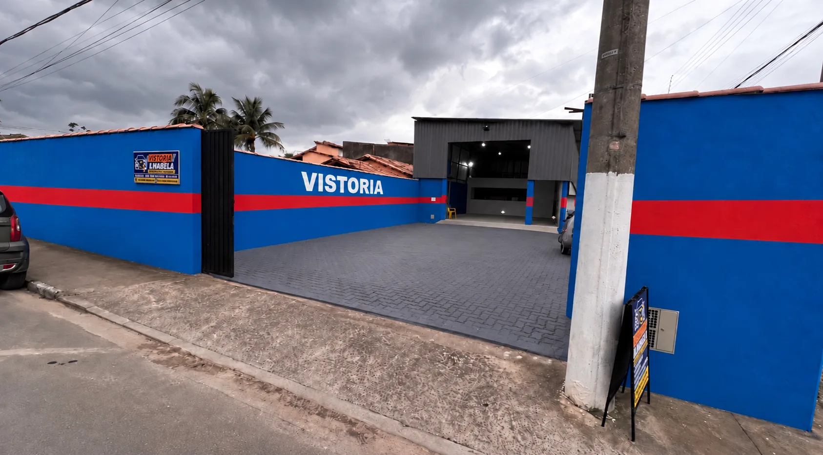 Fachada da Vistoria Veicular Ilhabela no Perequê, com muro azul e vermelho e a palavra VISTORIA